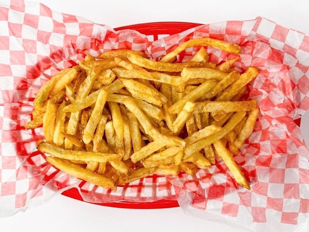 Papas fritas en un canasto rojo con papel damero.